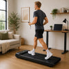 Man using a mini treadmill in a modern UK home office living room
